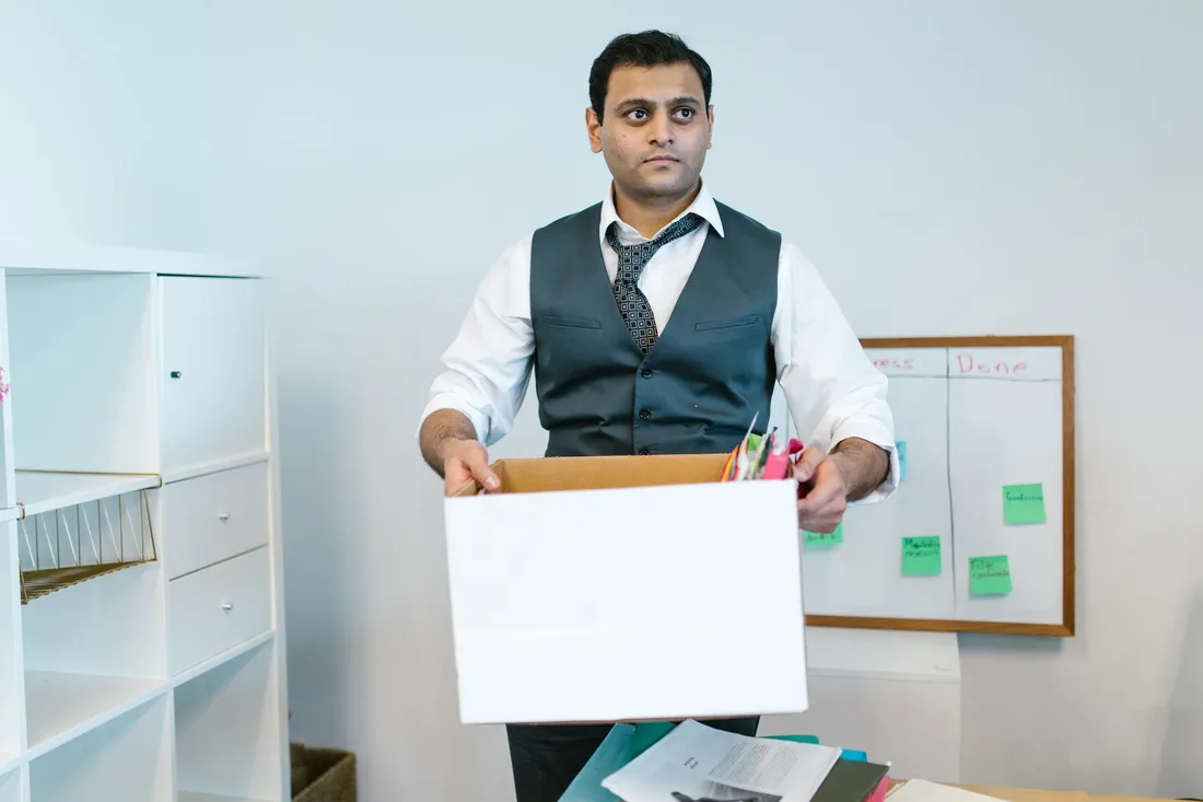 Gestapelte Umzugskartons und Bürostühle in einem leergeräumten Büro