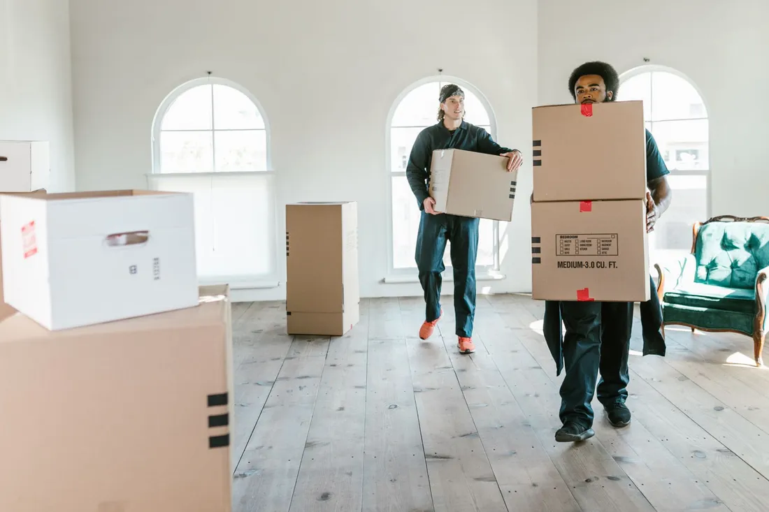 Umzugshelfer arbeitet zwischen Möbelteilen und Kartons